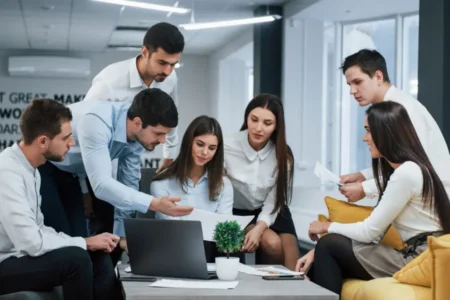 Guy shows document to a girl. Group of young freelancers in the office