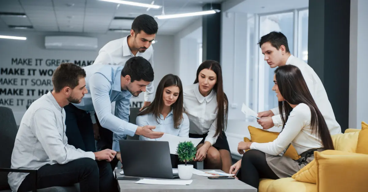 Guy shows document to a girl. Group of young freelancers in the office